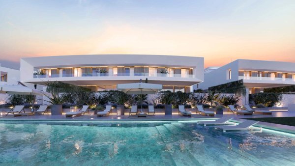 Buitenzicht op een moderne townhouse met een zwembad in Estepona, met weelderige beplanting en zonsondergang kleuren.