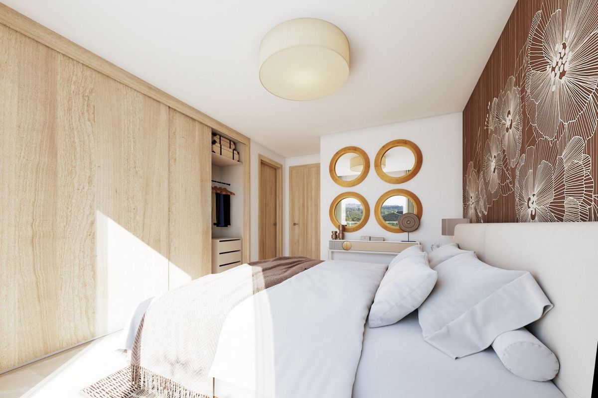 Gezellige slaapkamer met warme decoratie en ronde spiegels in een modern 3-slaapkamer penthouse in Mijas, Spanje.