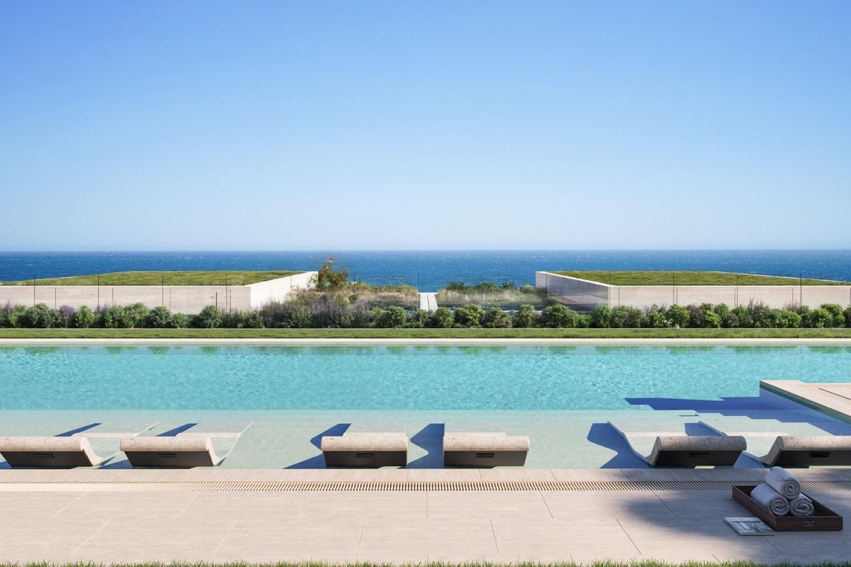 Stille zwembad met ligstoelen en oceaan op de achtergrond in Manilva, Costa del Sol.