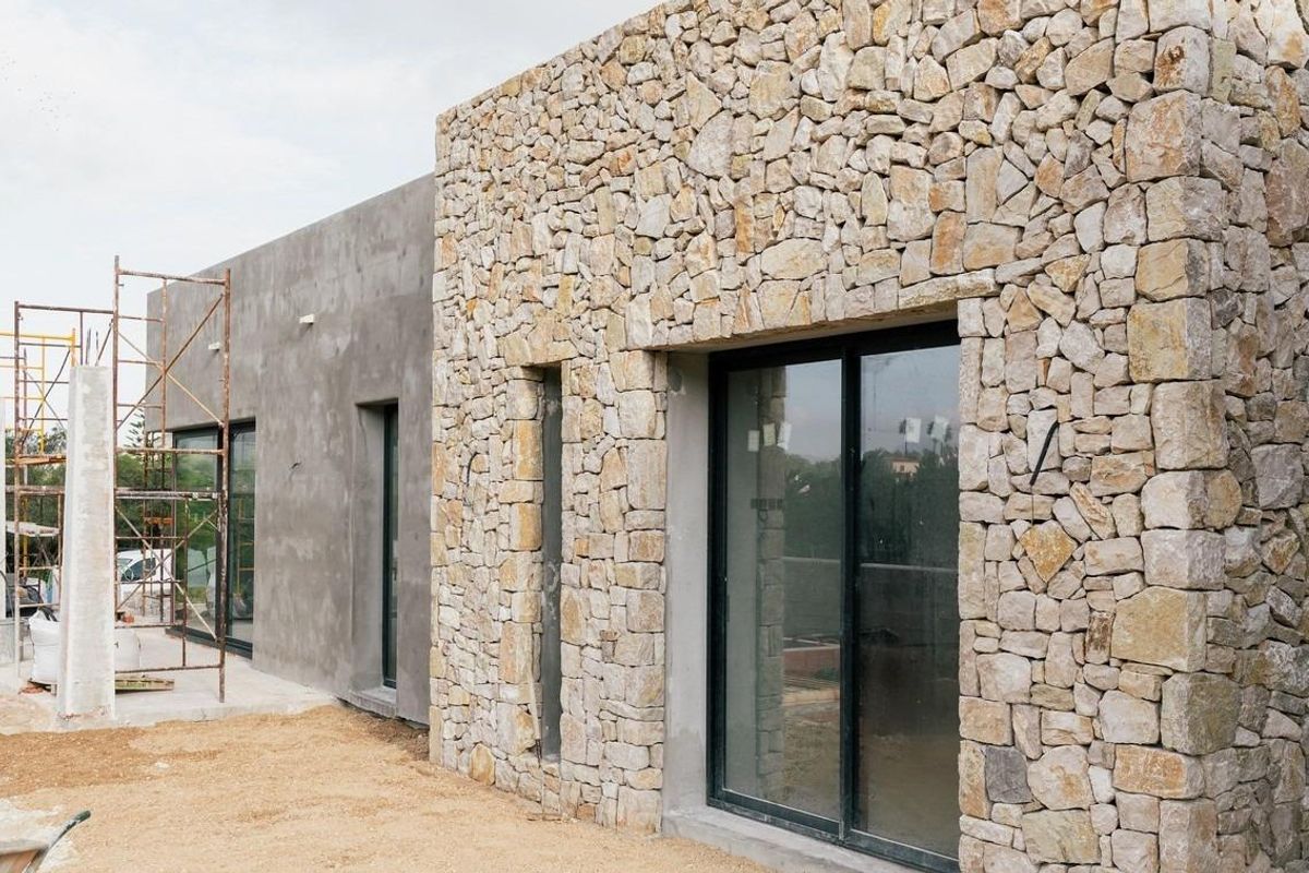 Zijaanzicht van een villa in aanbouw in Jávea, Costa Blanca Noord, met een mix van steen en moderne materialen.