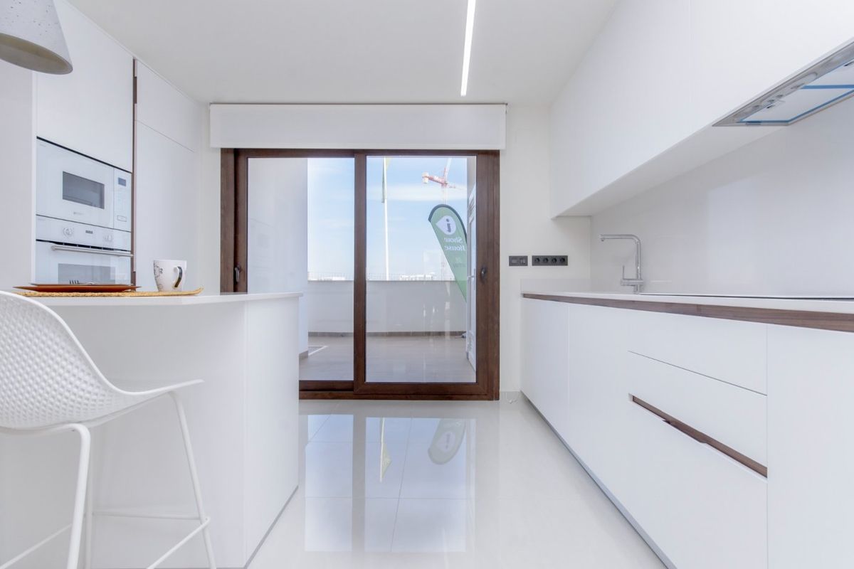 Moderne keuken van het appartement op de begane grond in Torrevieja, met strakke witte kasten en een eiland.