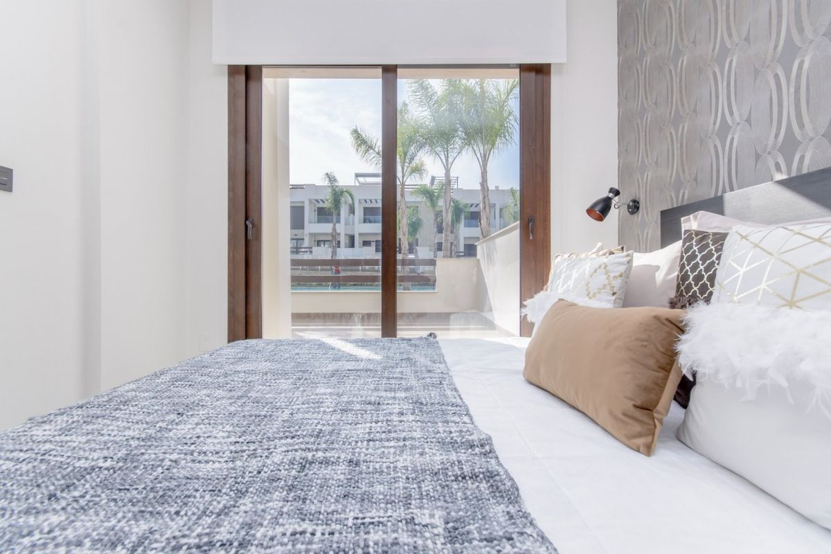 Gezellige slaapkamer in een 2-slaapkamer appartement in Torrevieja met uitzicht op het zwembad en moderne decoraties.