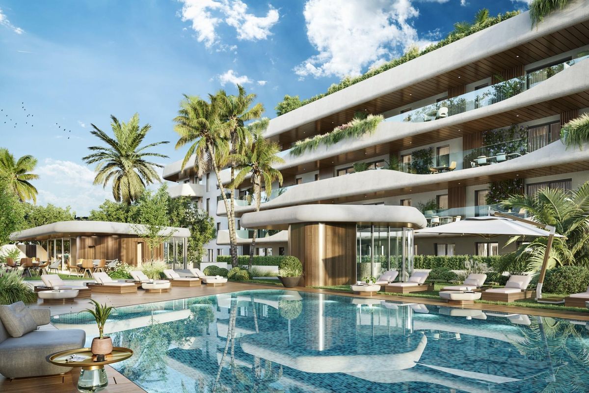 Aantrekkelijk zwembadgebied omgeven door ligstoelen en groen, onderdeel van een modern complex in Marbella, Spanje.