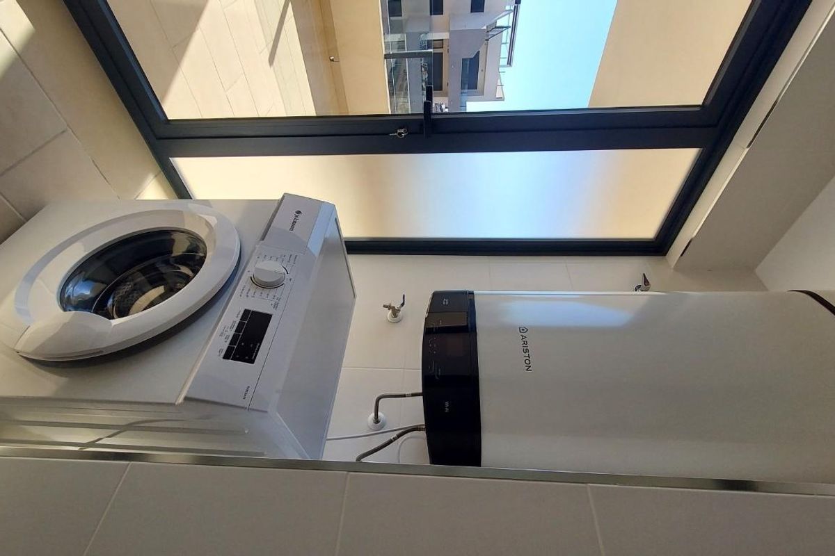 Wasruimte van het penthouse, met de wasmachine en boiler in helder licht.