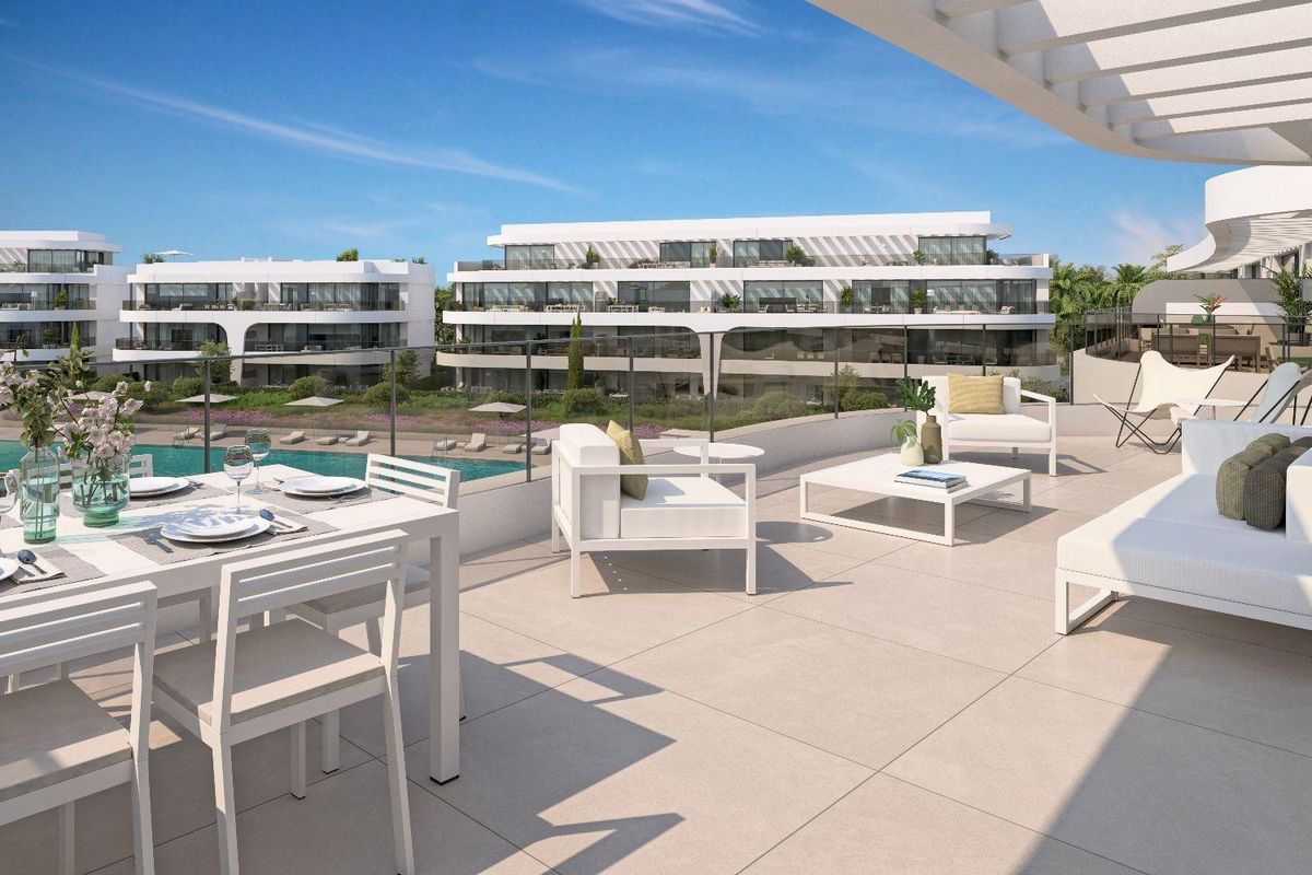 Ruimtelijk terras van een 3-slaapkamer penthouse in Estepona, Costa del Sol, met eet- en loungegedeelten met uitzicht op tuinen.
