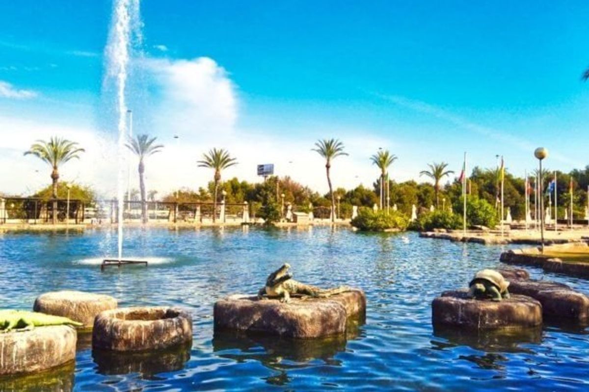 Schilderachtige vijver in Torrevieja versierd met standbeelden en omringd door groen en palmbomen.