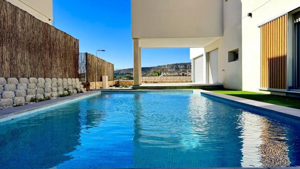 Blick auf einen glitzernden pool mit klarem blauem wasser, umgeben von moderner architektur in Algorfa, Costa Blanca.