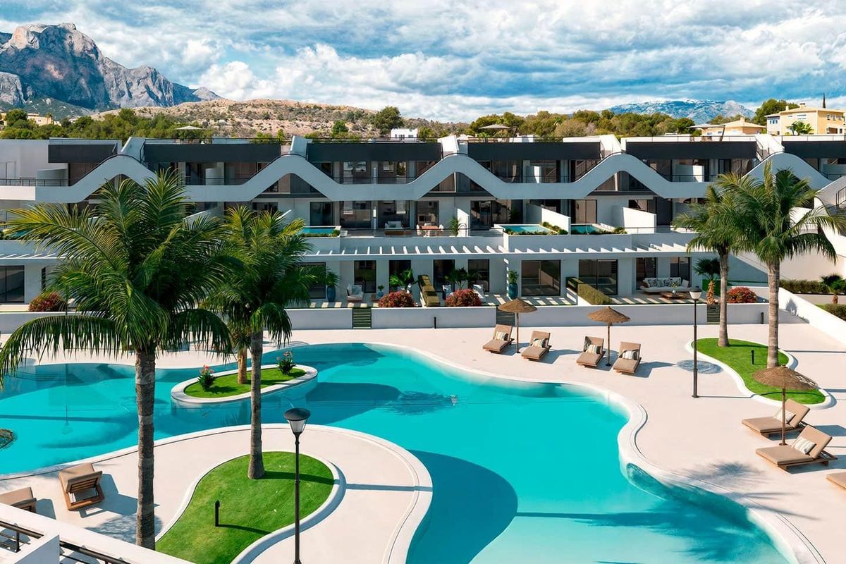 Uitzicht vanaf het zwembad van het appartementcomplex, met ligstoelen en palmbomen tegen de blauwe lucht in Alfas del Pi.