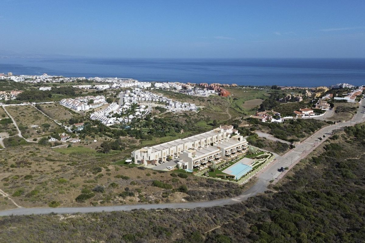 Luchtfoto van stadswoningen in Manilva, Costa del Sol, omgeven door natuurlandschap en oceaan.