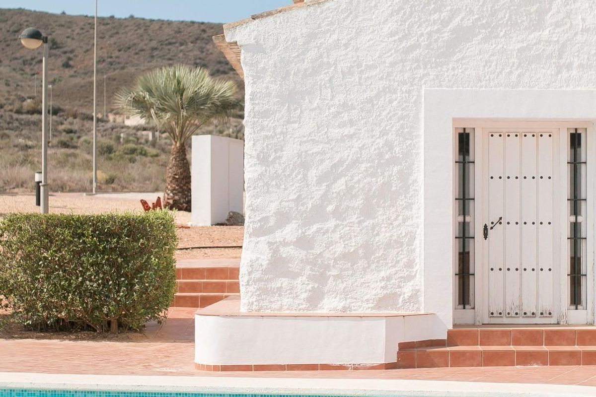 Fonkelend zwembad naast een wit gebouw in Fuente Álamo, met groen en palmbomen die het uitzicht verbeteren.