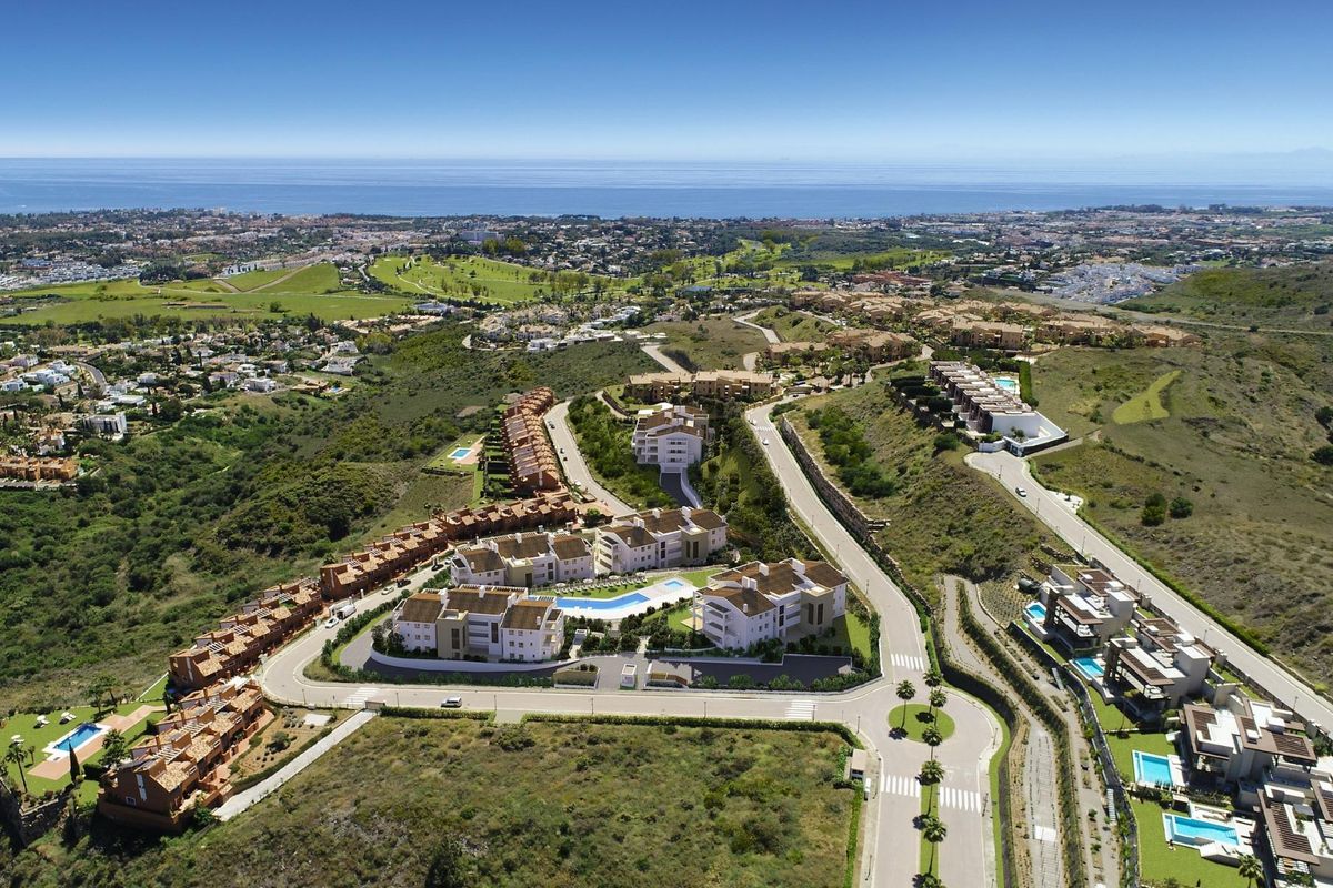 Luchtfoto van een woongebied met 2-slaapkamer appartementen te midden van groene heuvels in Benahavís, Costa del Sol.