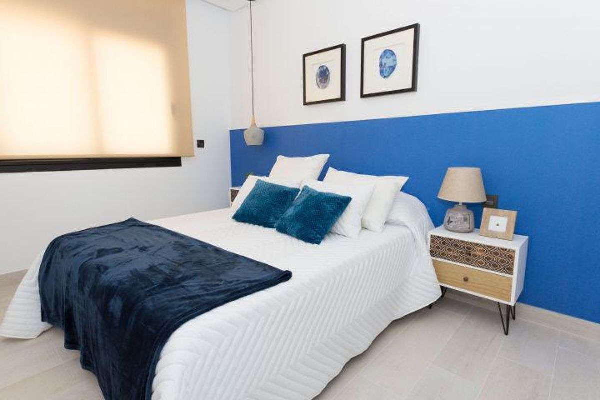 Moderne slaapkamer met blauwe accentmuur, wit beddengoed en decoratieve blauwe sierkussens in villa in Finestrat