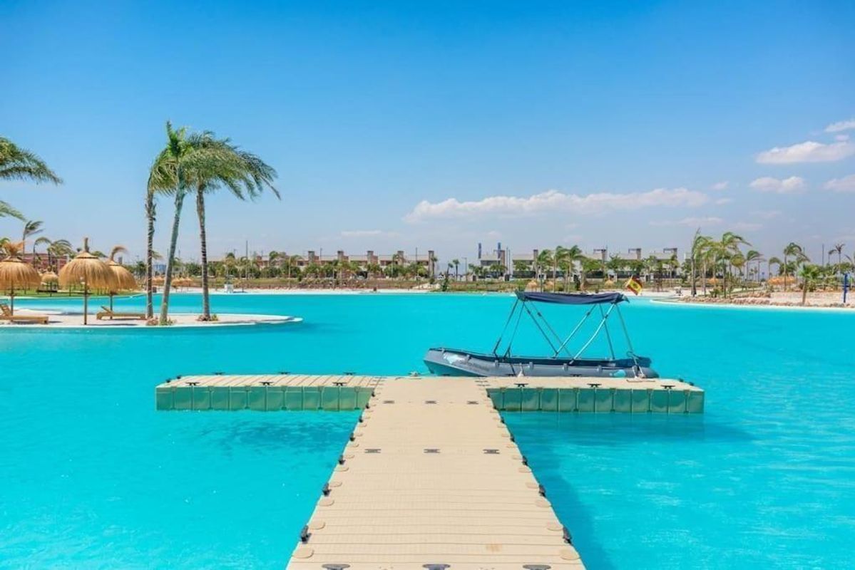 Aanlegplaats met boot en palmbomen in een levendige zwembadsetting in Torre Pacheco, Costa Calida.