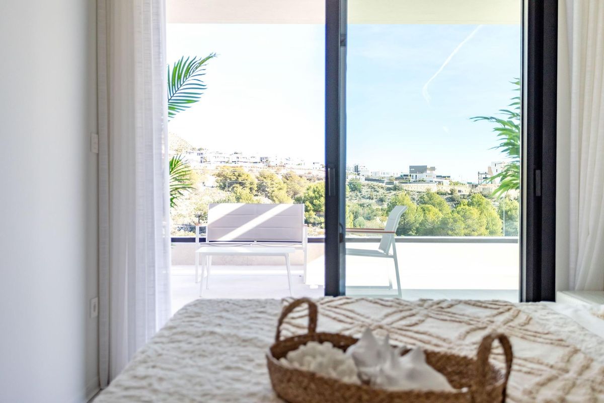 Prachtig uitzicht vanaf een slaapkamer met balkon dat het groene landschap toont in een 2-slaapkamerappartement in Finestrat, Costa Blanca.