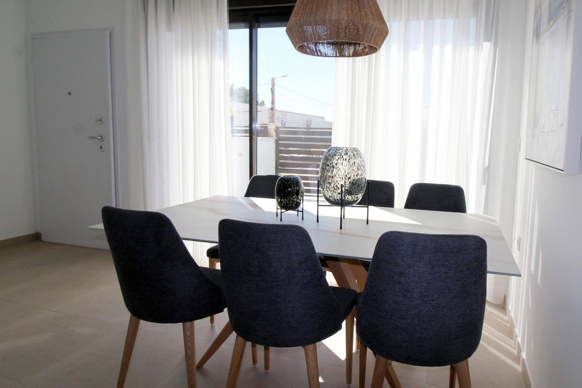 Chic eettafel met stijlvolle stoelen en verlichtingsarmatuur in een ruime 3-slaapkamer herenhuis in Pilar de La Horadada.