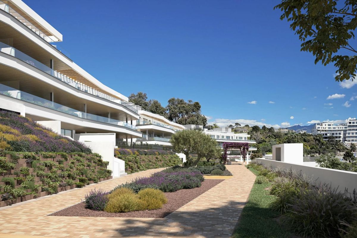 Pad omringd door planten dat naar moderne appartementen leidt en een vredige sfeer biedt in Estepona, Spanje.