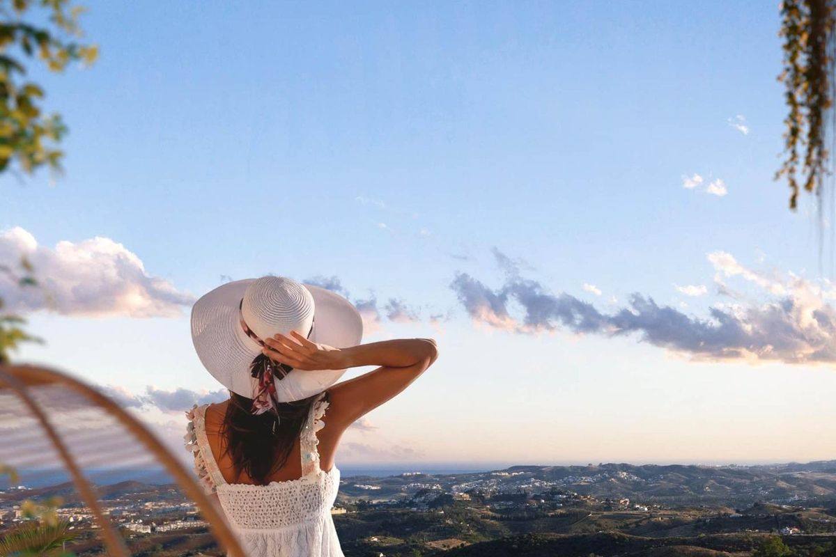 Persoon die geniet van het uitzicht vanaf een terras versierd met planten, dat de rust van Mijas, Costa del Sol vastlegt.