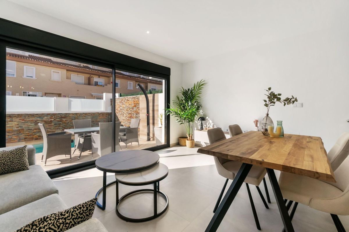 Moderne woonruimte met grote ramen en eetgedeelte dat uitkomt op het terras van een townhouse in San Pedro del Pinatar.