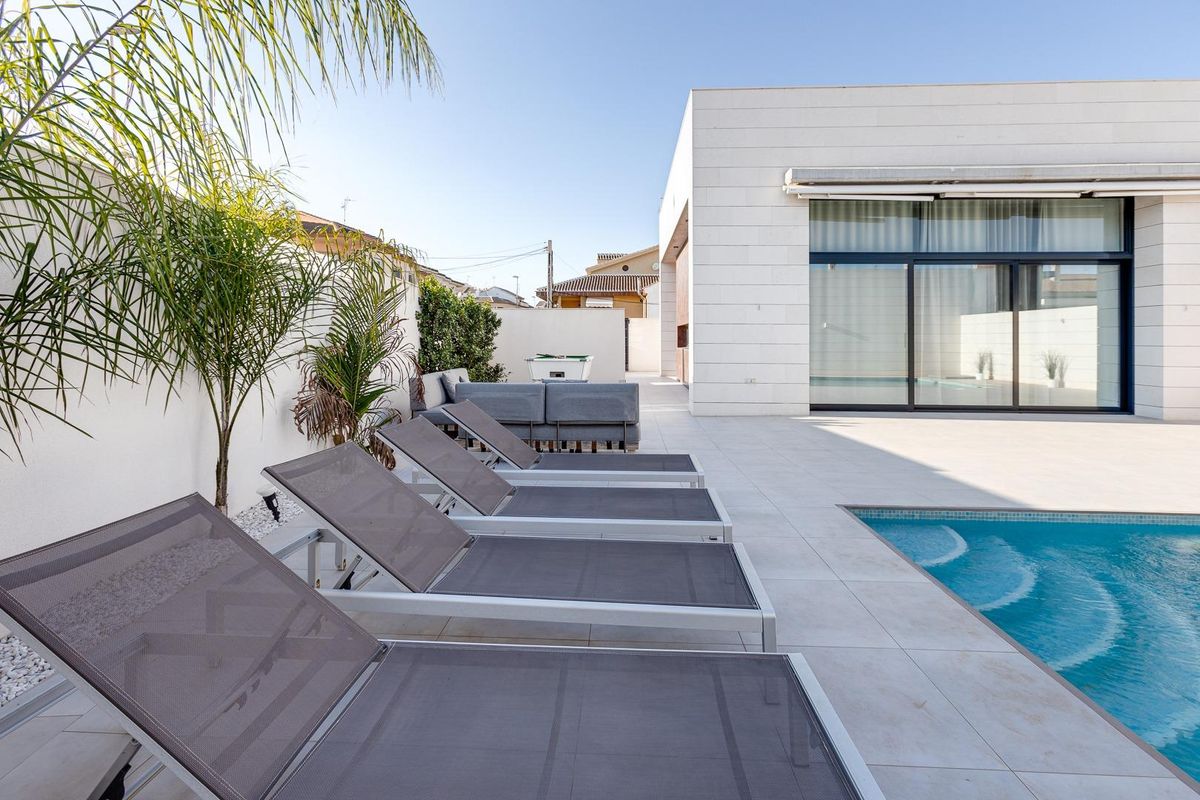 Zonnig terras met ligstoelen naast het zwembad bij de 3-slaapkamer villa in Pilar de La Horadada.