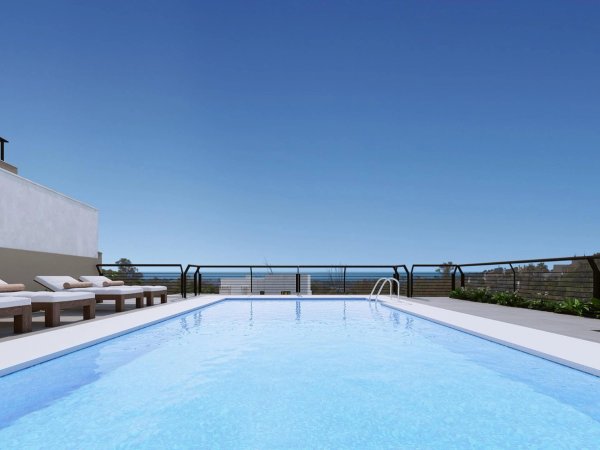 Penthouse zwembad met ligstoelen onder een heldere lucht in Marbella, Costa del Sol.