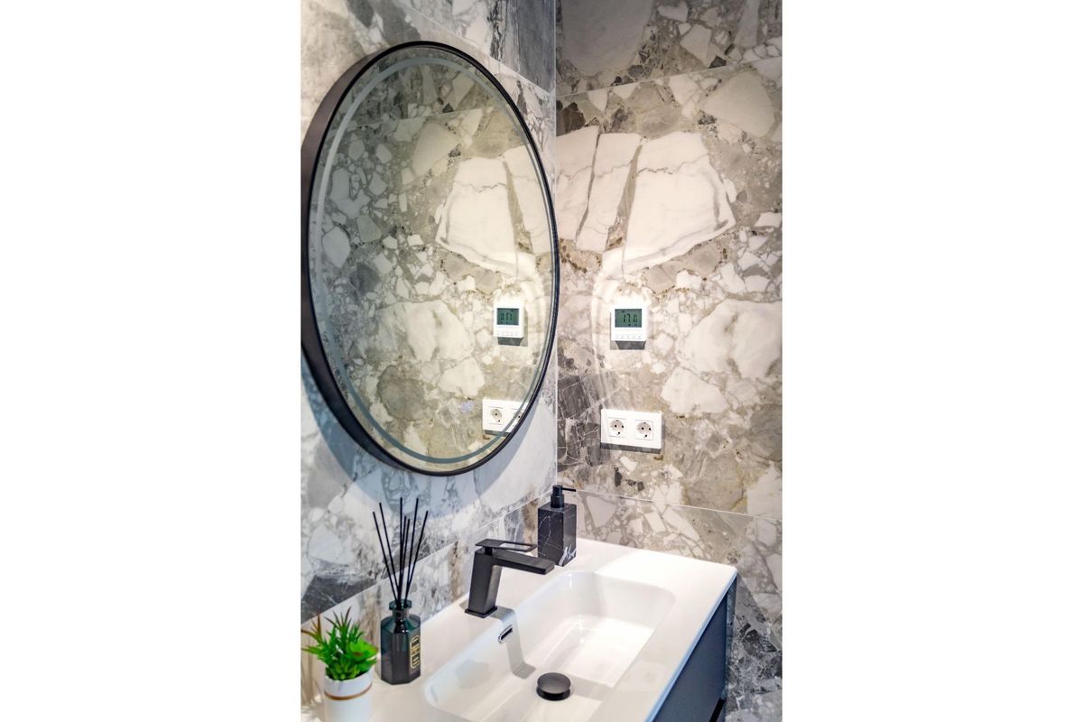 Moderne badkamer met marmeren wanden en een ronde spiegel in een 2-slaapkamerappartement in Finestrat, Costa Blanca Noord.