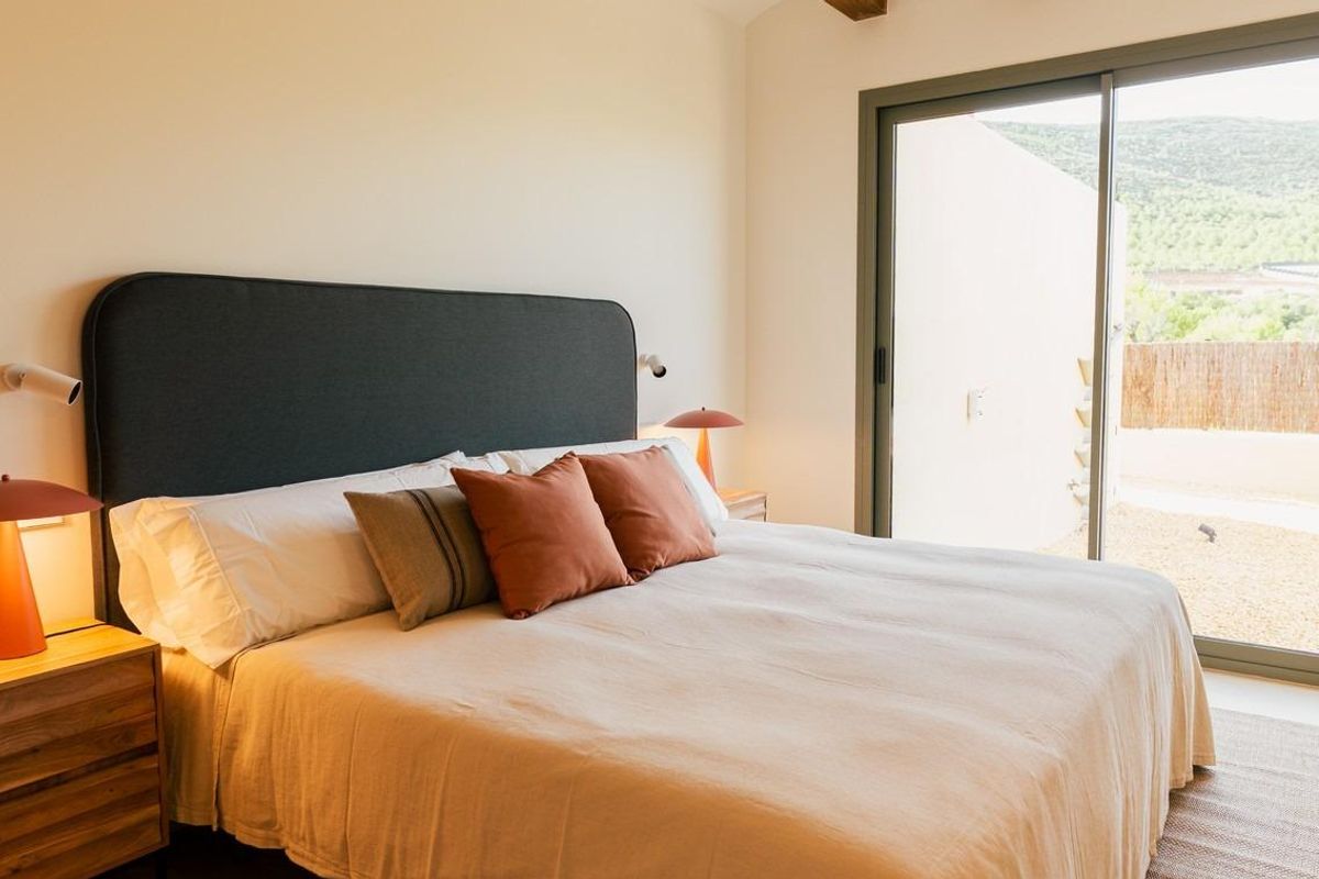 Gezellige slaapkamer met houten balken en schuifdeuren naar de tuin in Jávea.