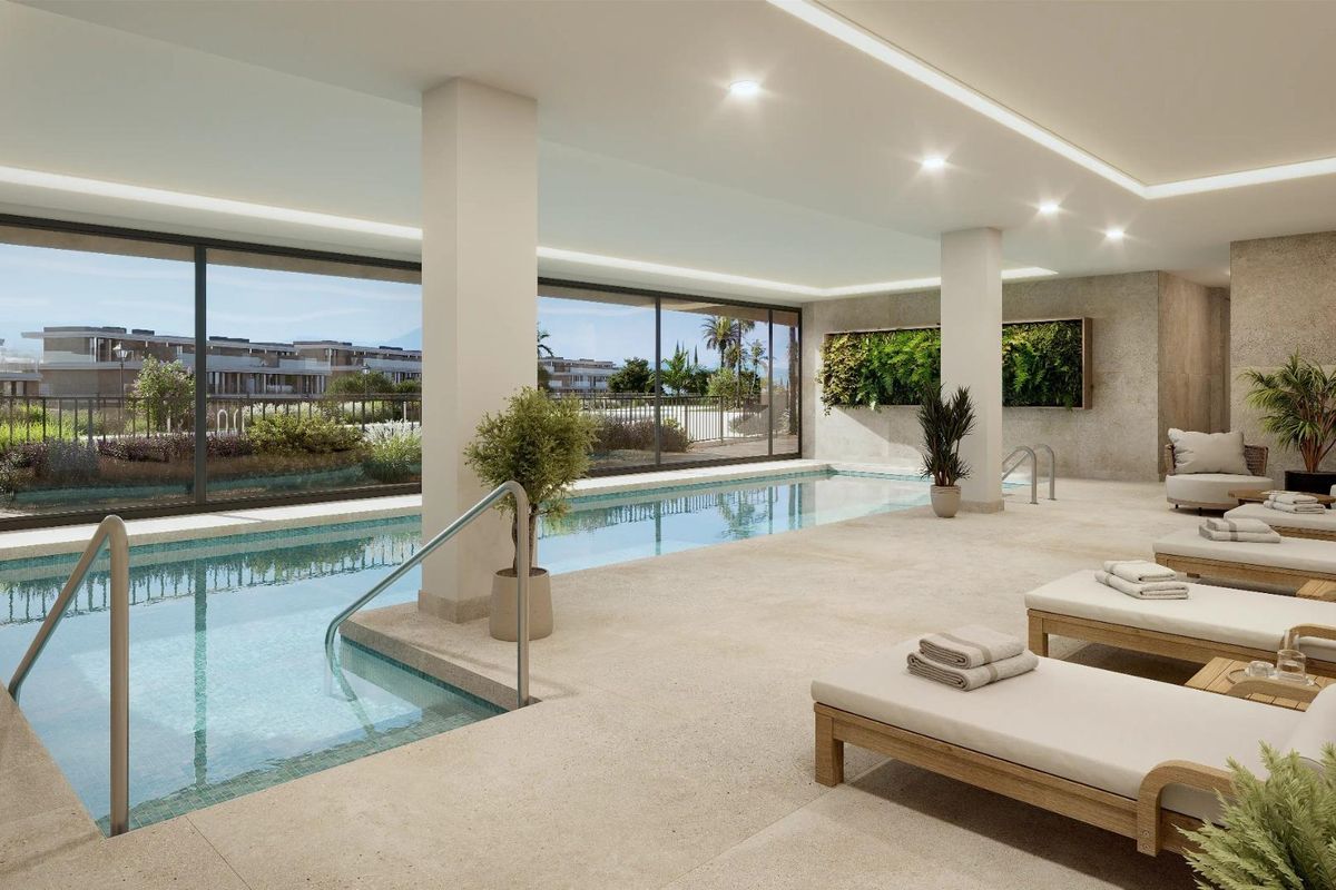 Binnen ontspanningsruimte met zwembad en ligstoelen in een woongebouw in Estepona.