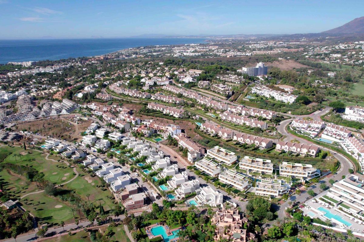 Luchtfoto van een woongebied in Estepona met golfbanen en townhouses langs de kustlijn.