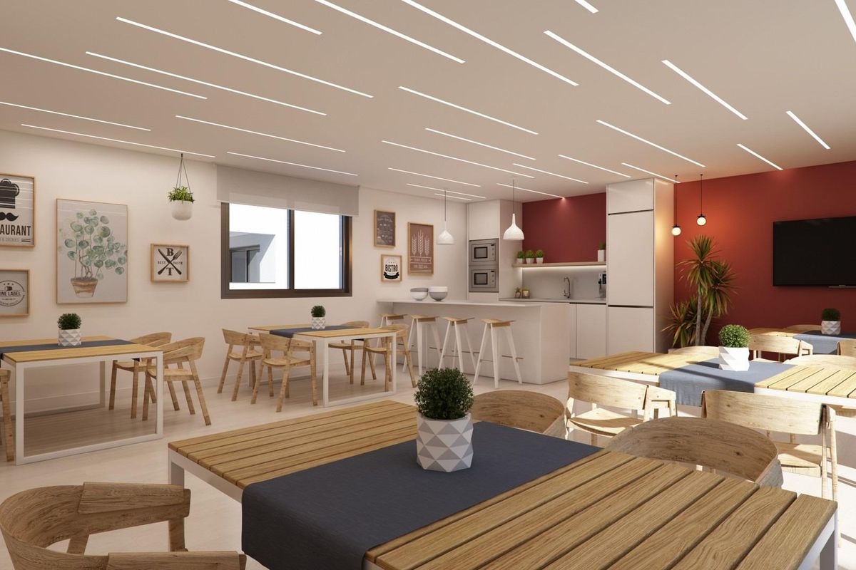 Heldere eetruimte met houten tafels en stoelen, en een moderne keuken op de achtergrond in Casares.