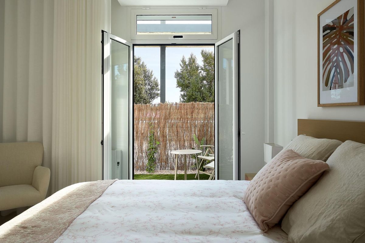 Stille slaapkameruitzicht vanuit een 3-slaapkamer appartement in Vera, met deuren naar een tuin en comfortabele zitplaatsen.