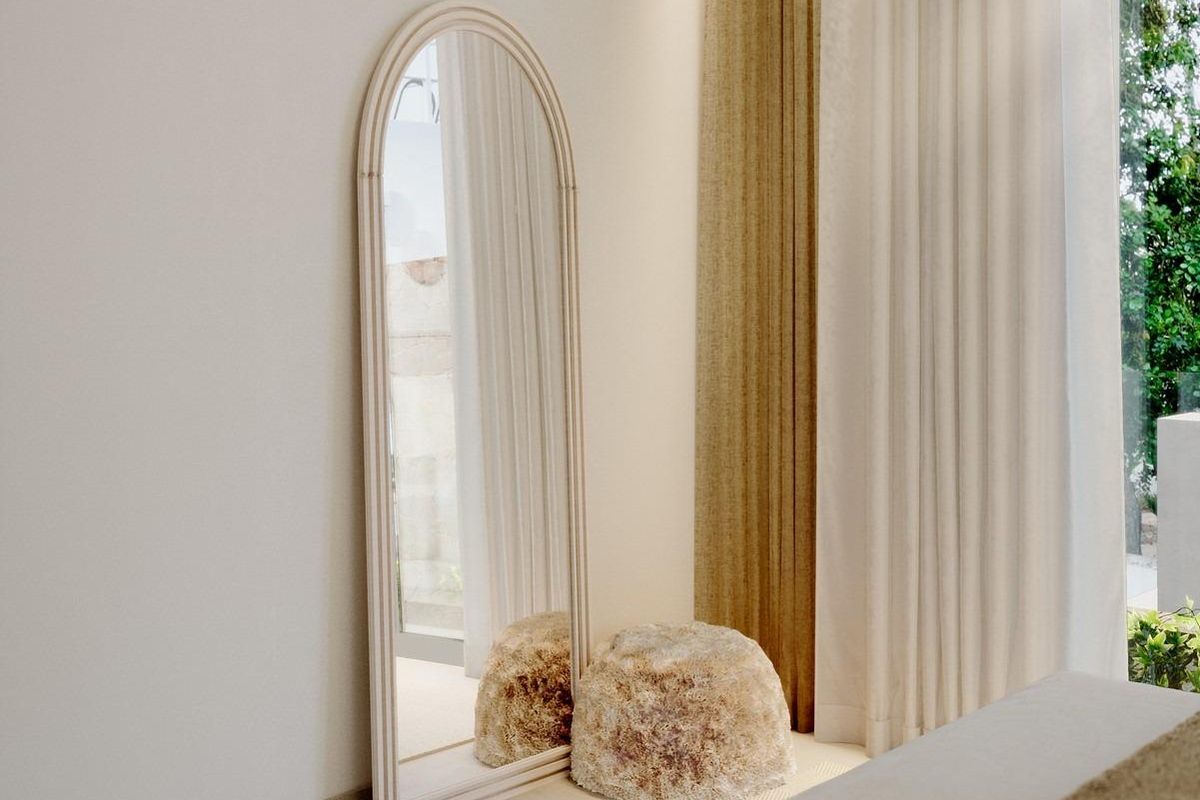 Heldere hoek in de slaapkamer met een stijlvolle spiegel en zachte gordijnen in de townhouse in Mojacar.