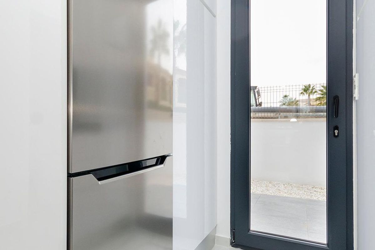 Heldere ruimte met een koelkast en een deur naar buiten in een moderne 3-slaapkamer villa in Torrevieja, Costa Blanca.