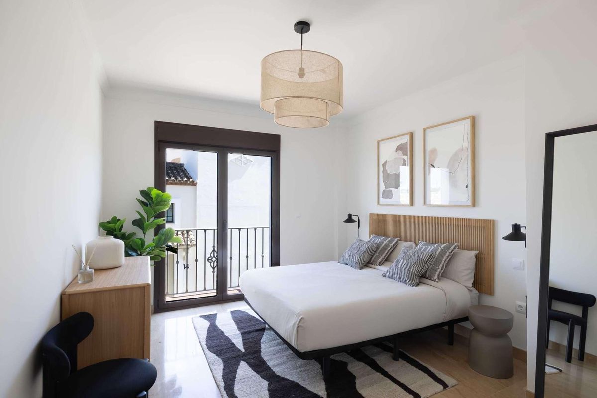 Helder slaapkamer in een townhouse in Estepona met een tweepersoonsbed, moderne inrichting en toegang tot een balkon.