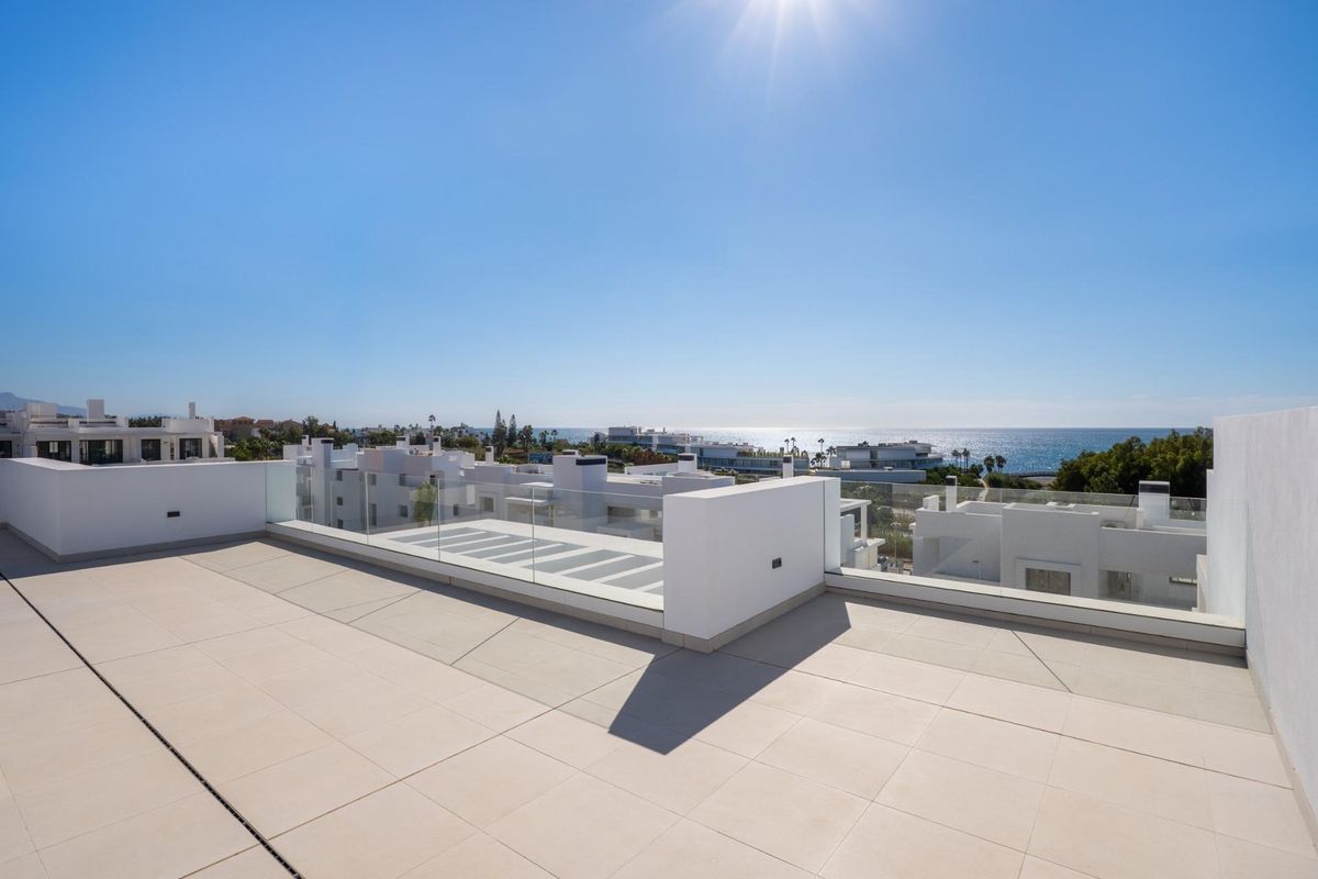 Ruim terras in het penthouse van Estepona met panoramisch uitzicht op de kust onder een heldere blauwe lucht.