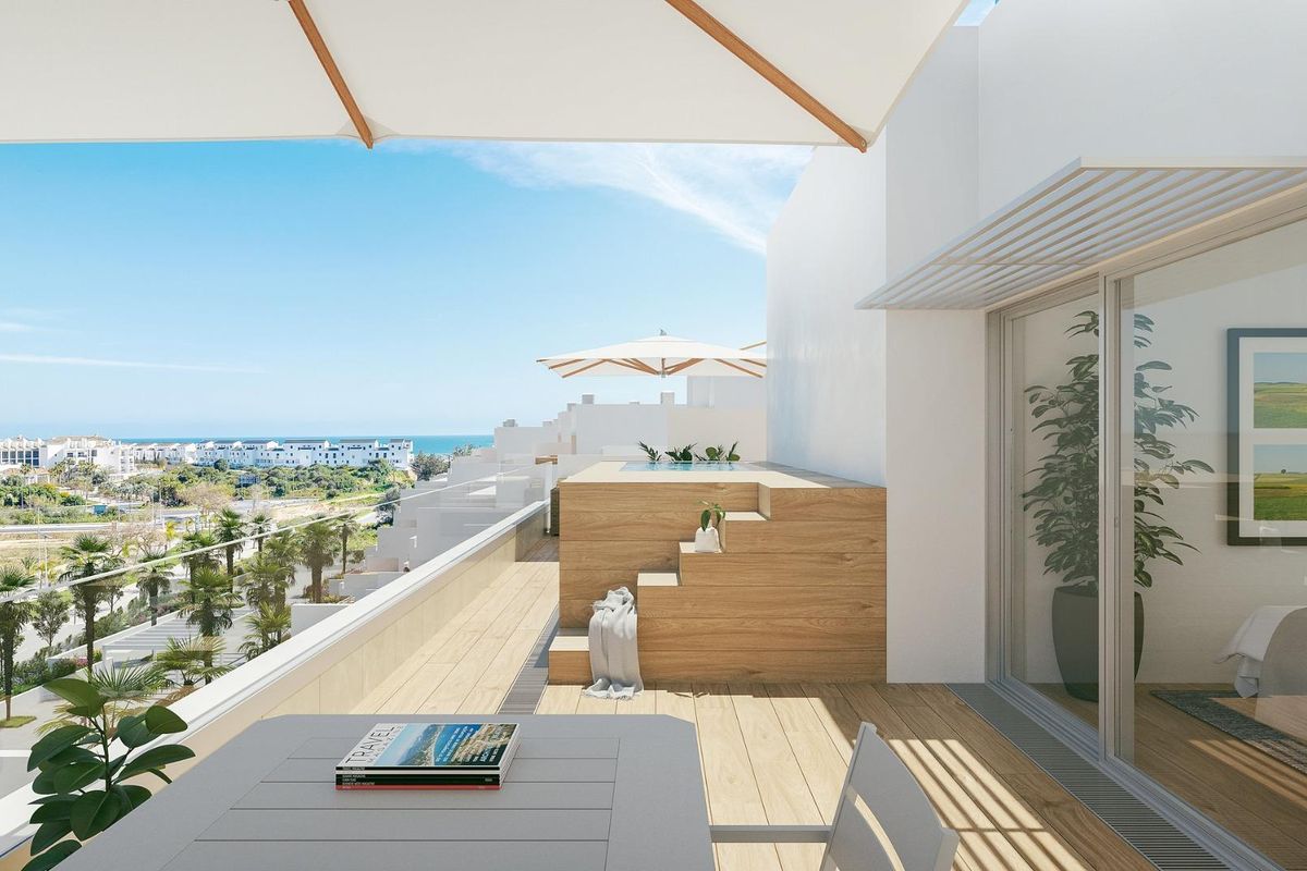 Zonnig terras van een hedendaags Estepona appartement met houten vloer en uitzicht op zee.