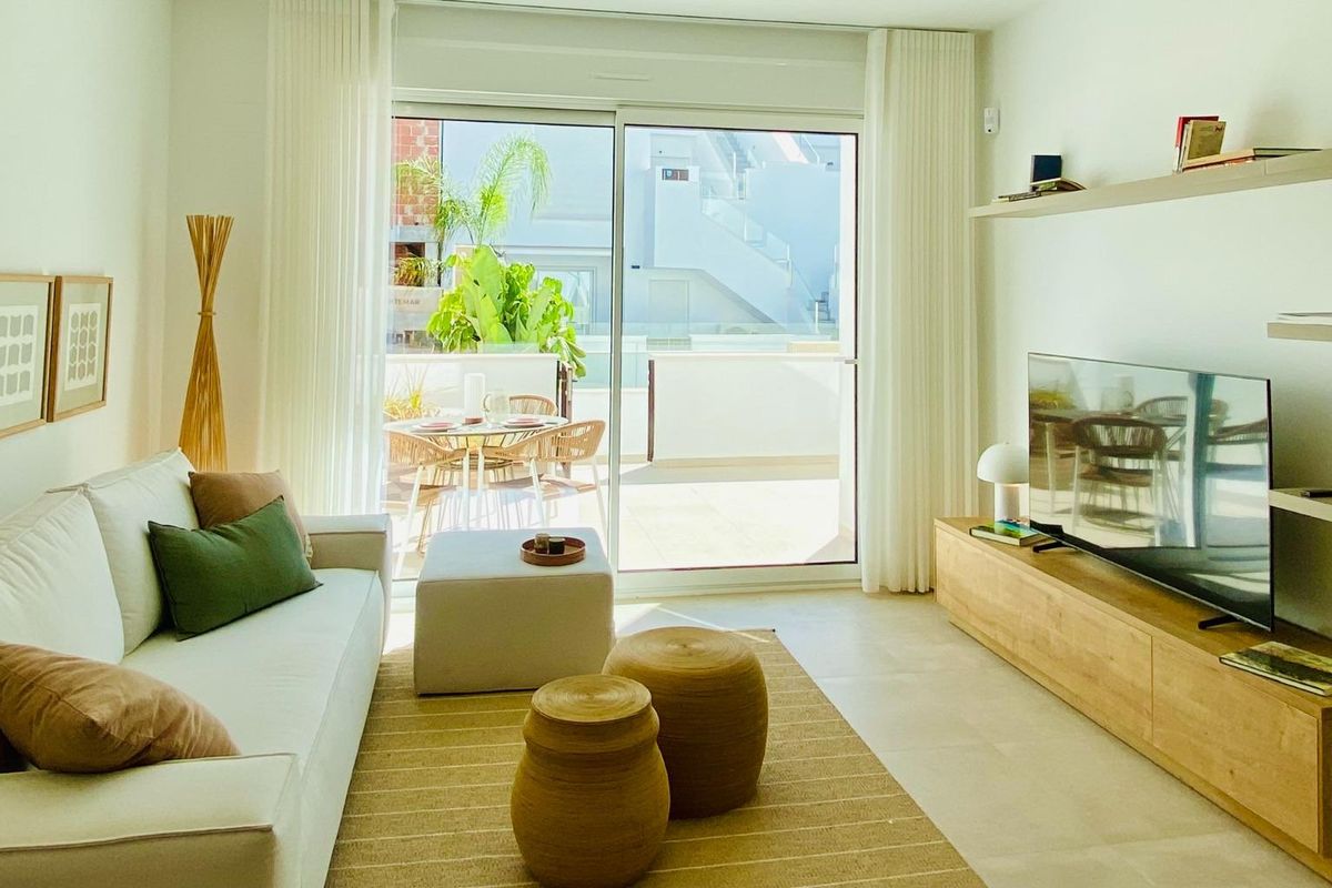 Heldere woonkamer met een moderne bank en een groot raam, verbonden met het terras in Pilar de La Horadada.