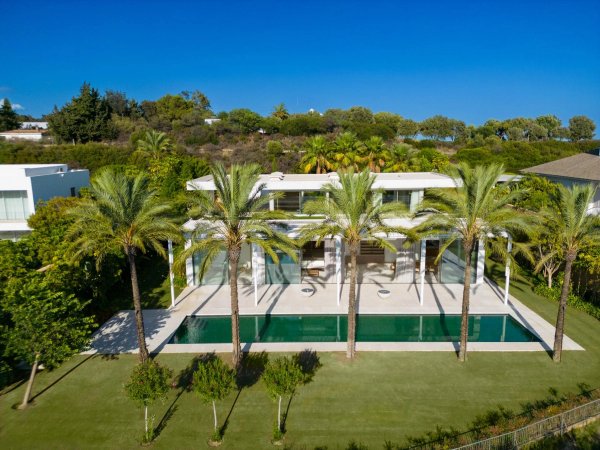 Luchtfoto van een moderne 4-slaapkamer villa in Casares met een zwembad en palmbomen.