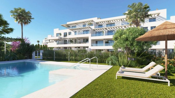 Modern wit appartementencomplex met zwembad, palmbomen en ligbedden in Mijas, Costa del Sol