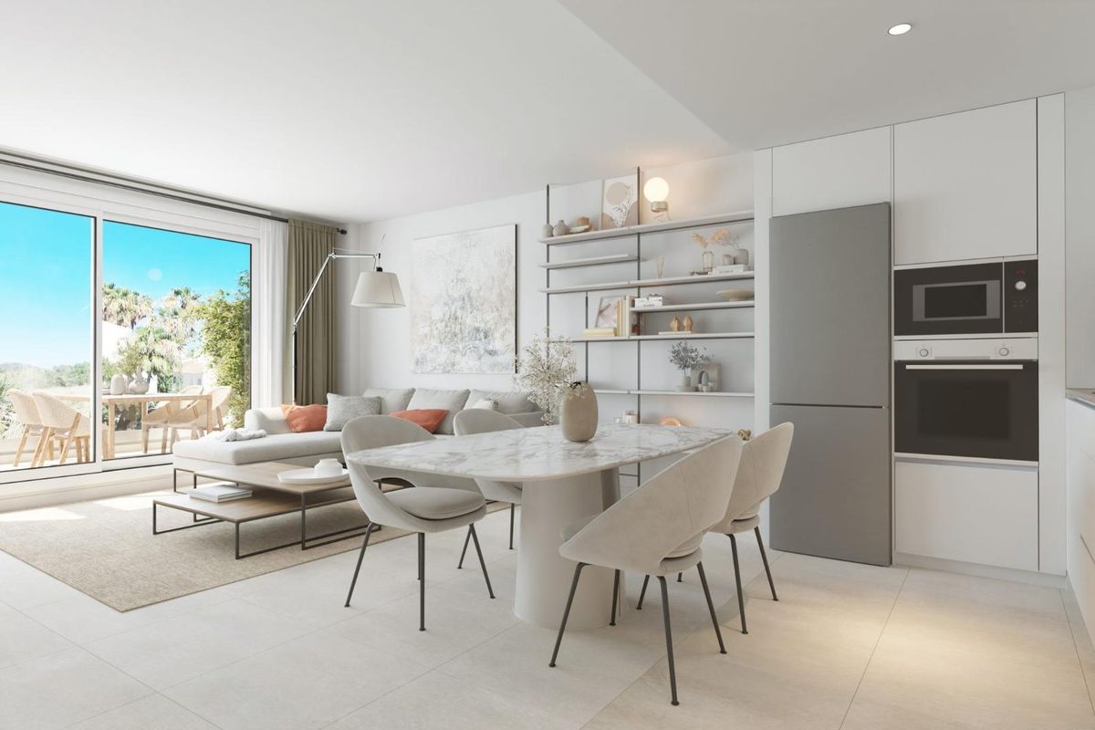 Open keuken en eetkamer met marmeren tafel, witte stoelen en schuifdeuren in appartement aan de Costa del Sol