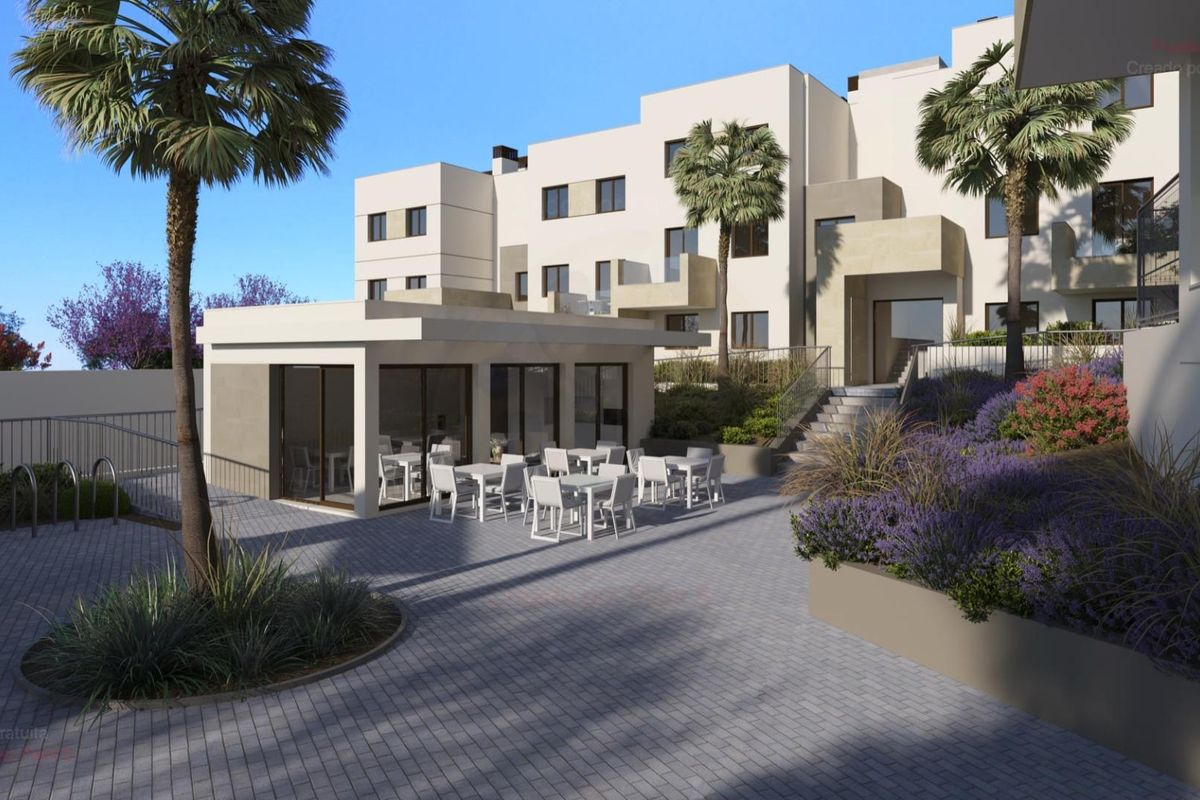 Geplaveide cour met zitplaatsen buiten penthouses in Estepona, met tropische plantenopstellingen.