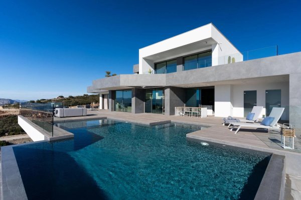 Stunning exterior view of a 4-bed villa in Benitachell with an infinity pool and mountain views.