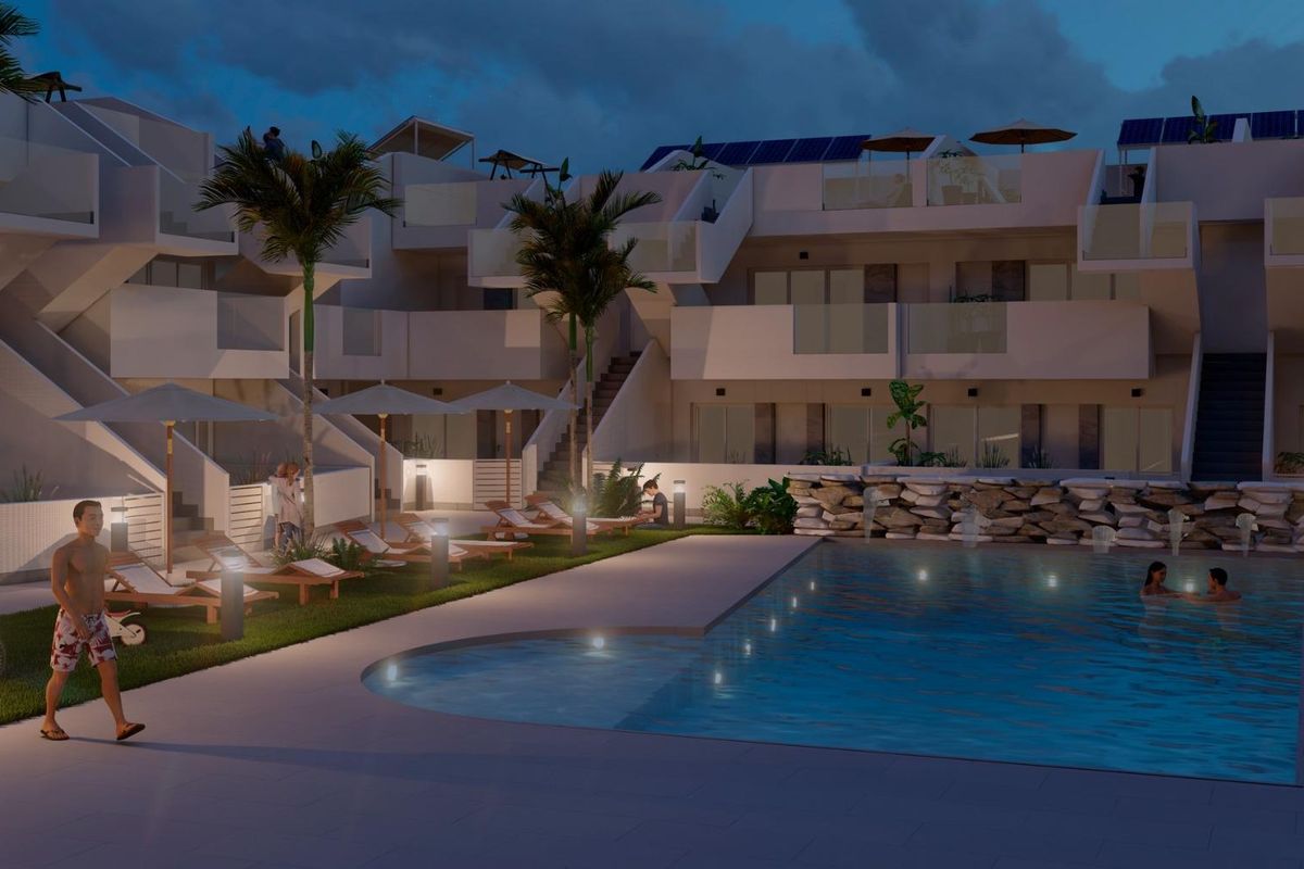 Nachtzicht op het zwembadgebied van het appartementencomplex in Torre Pacheco, met verlichte ligstoelen en palmbomen.