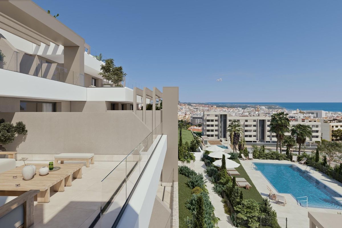 Terraszicht van een modern appartement in Estepona, met het zwembadgebied en de kustlijn in de verte.