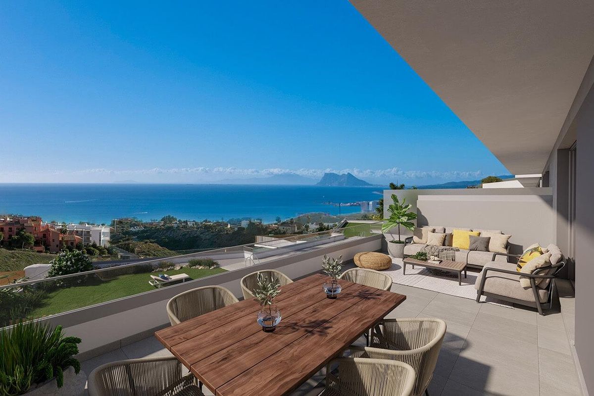 Ruime terras van een moderne stadswoning in Manilva, met houten eettafel, zeezicht en kustlandschap