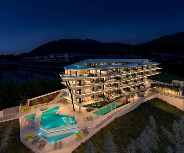 Modern appartementencomplex in Fuengirola met prachtig zwembad en tuinen, verlicht in de nacht.