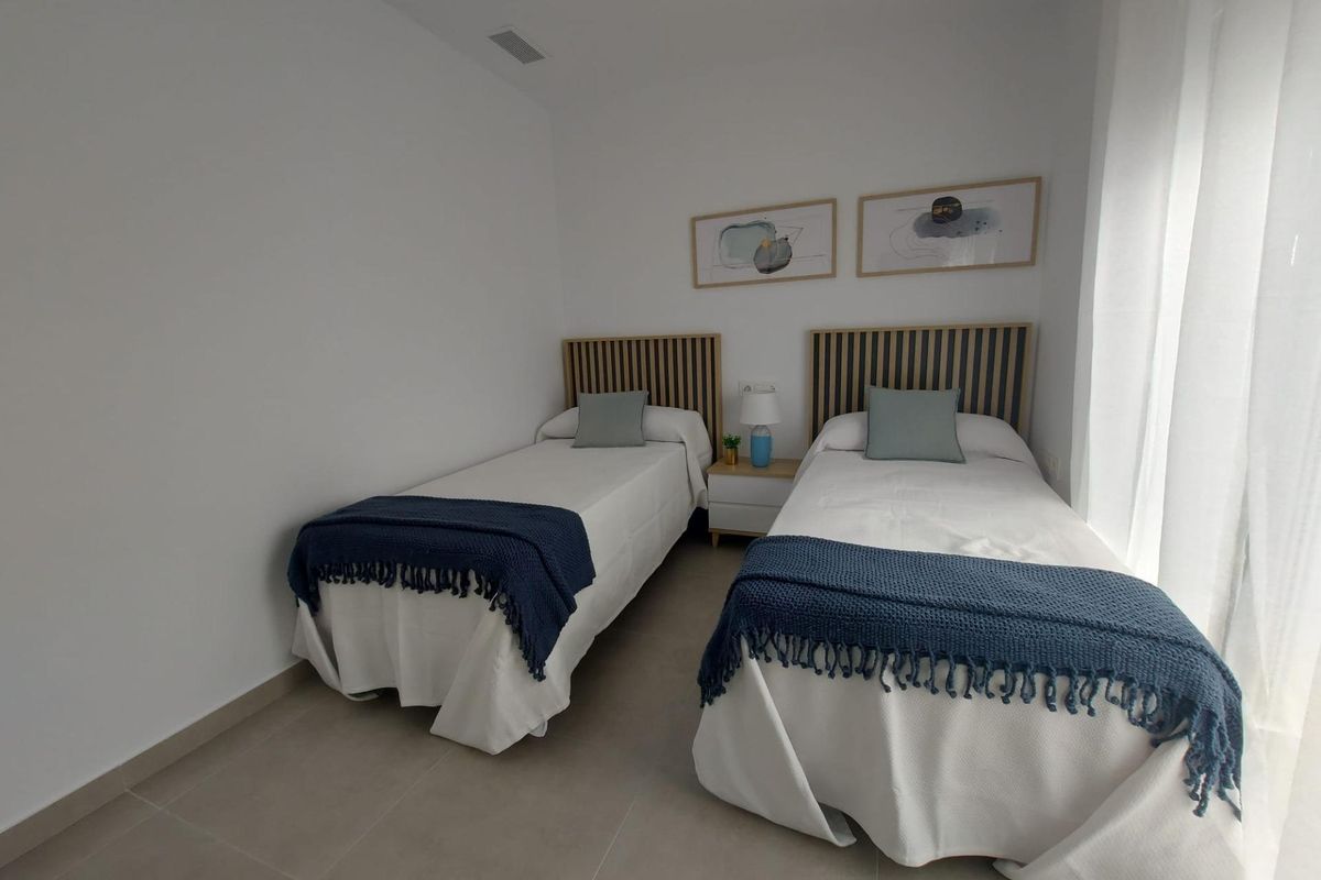 Uitnodigende slaapkamer met twee bedden in warme tinten in een 2-slaapkamer townhouse in Torre Pacheco, Spanje.