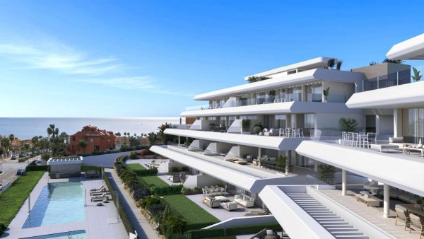 Uitzicht op het moderne appartementencomplex in Estepona met een zwembad en de oceaan op de achtergrond.