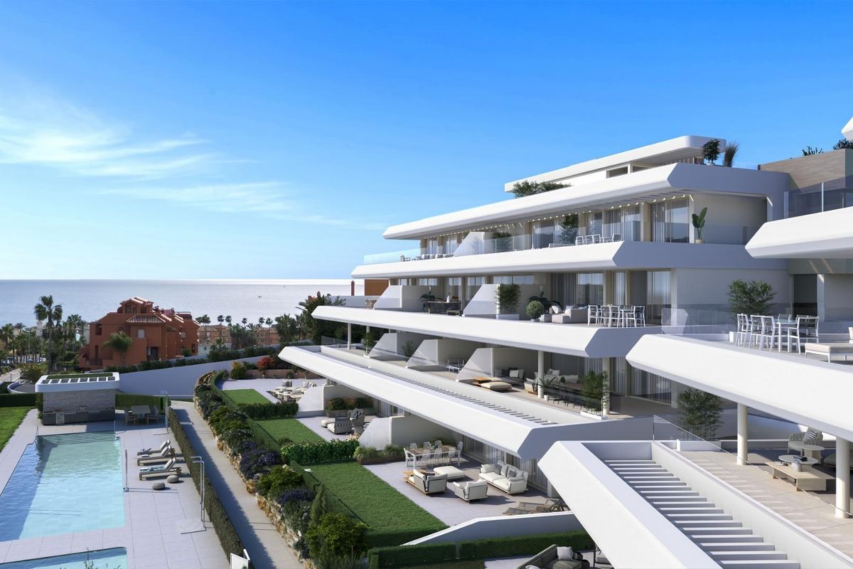 Uitzicht op het moderne appartementencomplex in Estepona met een zwembad en de oceaan op de achtergrond.