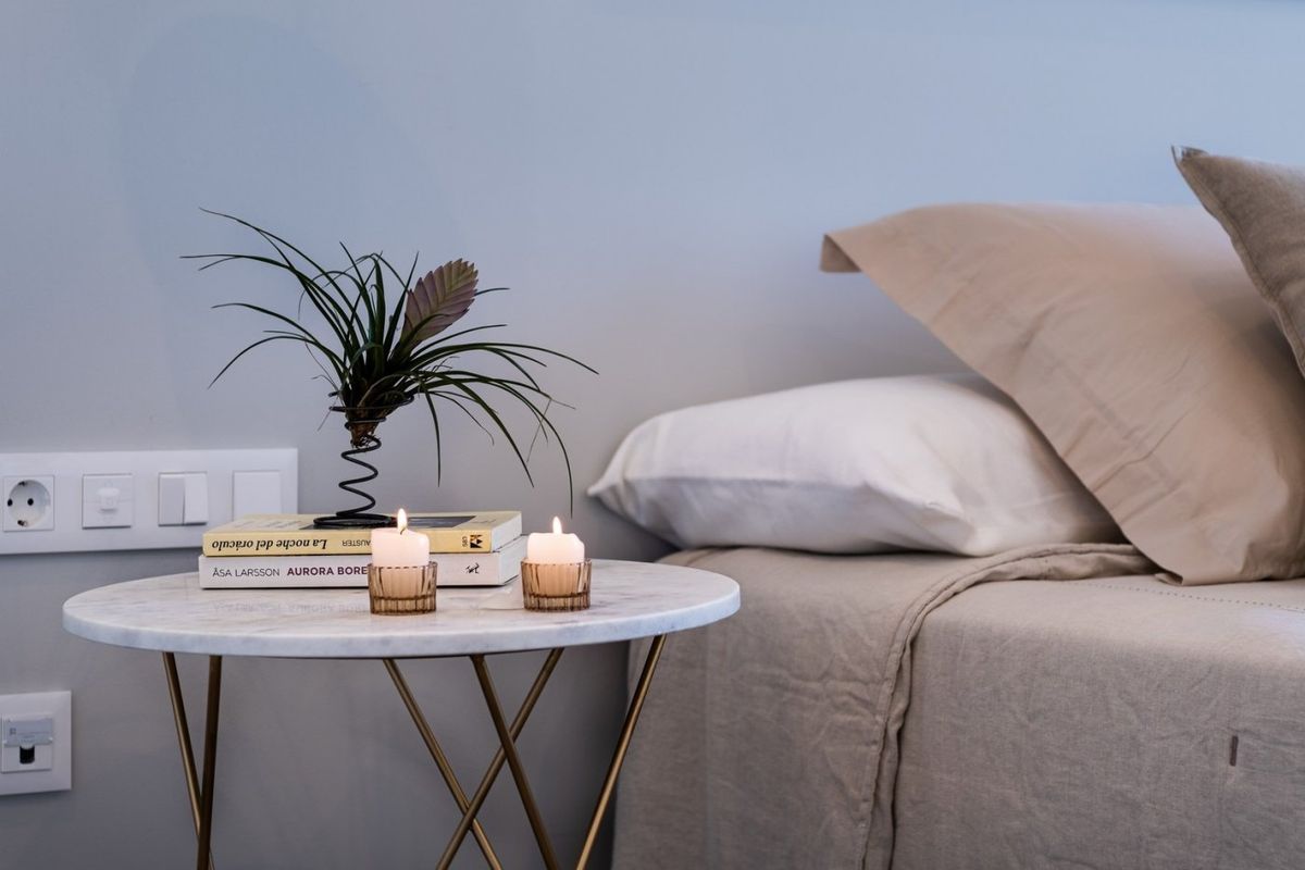 Stijlvolle nachtkastdecoratie in een slaapkamer van een 3-slaapkamer villa, met kaarsen en groen, gelegen in Polop, Spanje.