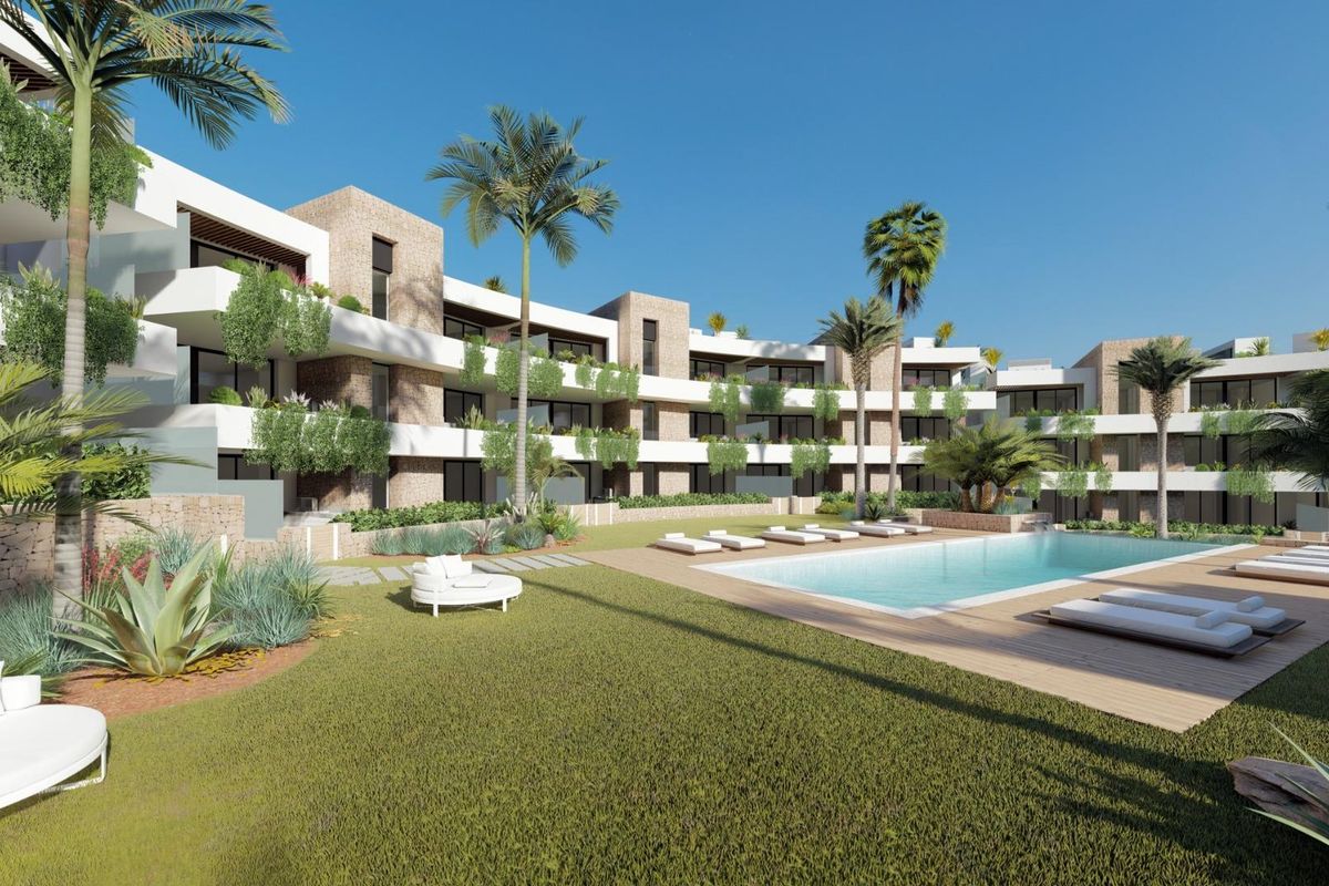 Buitenruimte met ligbedden rond een zwembad en de moderne appartementen gevel in La Manga Club, Spanje.